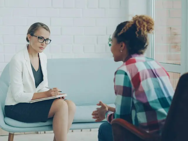 A therapist and a client talking during a session in a bright room